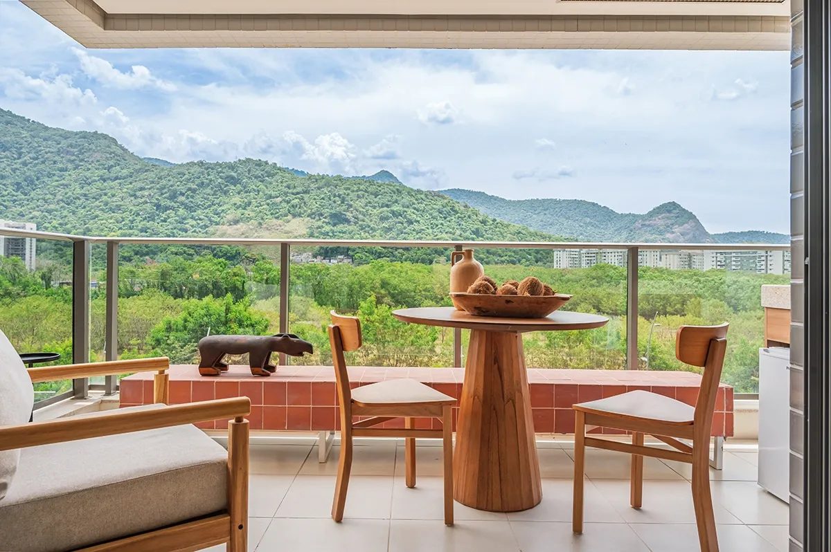 Perspectiva ilustrada da varanda de um apartamento, com mesa posta e vista para a serra